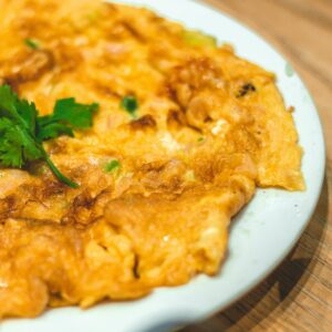 A mouthwatering Taiwanese omelet garnished with fresh cilantro, perfect for Asian cuisine enthusiasts.